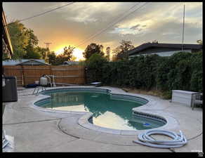 Pool at dusk featuring a diving board, a patio, and central air condition unit