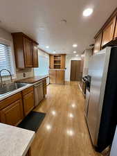 Kitchen featuring appliances with stainless steel finishes, light hardwood / wood-style floors, sink, and a textured ceiling