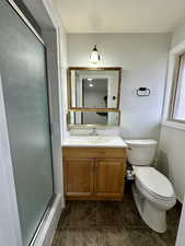 Bathroom with vanity, toilet, and a shower with door