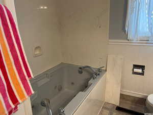 Bathroom featuring a tub to relax in, toilet, and tile patterned flooring