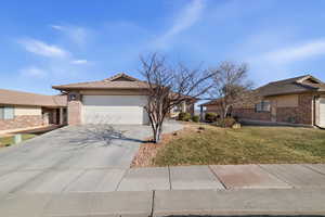 Single story home with a garage and a front lawn