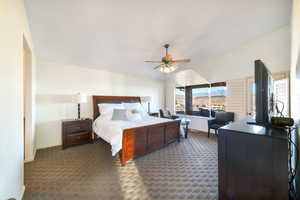 Bedroom featuring vaulted ceiling, carpet flooring, and ceiling fan