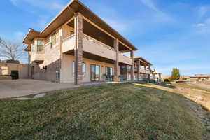 Back of house with a yard, a patio area, and a balcony