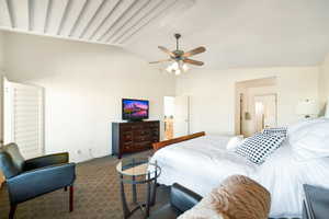 Bedroom featuring lofted ceiling, ensuite bath, ceiling fan, and carpet