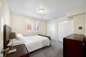 Bedroom featuring multiple closets, dark carpet, and a textured ceiling