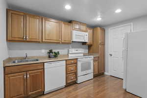 Kitchen featuring white appliances, wood-type flooring, and sink