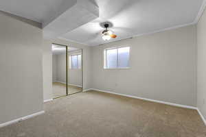 Unfurnished bedroom featuring carpet floors, ornamental molding, a closet, and ceiling fan