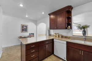 Kitchen featuring sink, light stone counters, white dishwasher, and kitchen peninsula