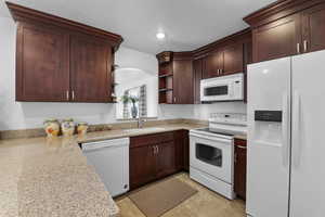 Kitchen with light stone countertops, sink, a textured ceiling, and white appliances