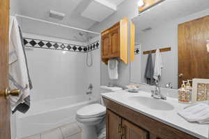 Full bathroom with tile patterned flooring, vanity,  shower combination, toilet, and a textured ceiling