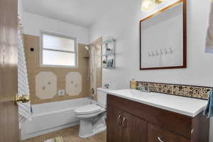 Full bathroom with tile patterned floors, toilet, tiled shower / bath combo, and vanity