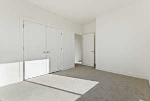 Unfurnished bedroom with light colored carpet and a closet