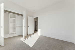 Unfurnished bedroom with light colored carpet and a closet