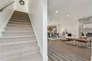 Stairway featuring hardwood / wood-style flooring and a stone fireplace