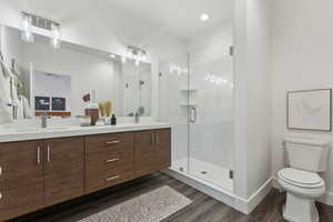 Bathroom with an enclosed shower, vanity, hardwood / wood-style flooring, and toilet