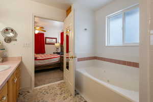 Bathroom with a tub, ceiling fan, and vanity