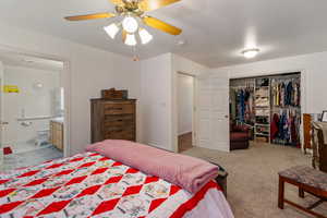 Carpeted bedroom with ceiling fan, ensuite bathroom, and a closet