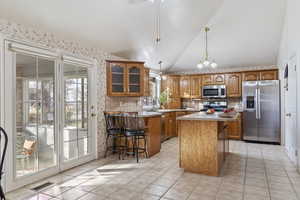 Kitchen with backsplash, a kitchen breakfast bar, stainless steel appliances, and a center island