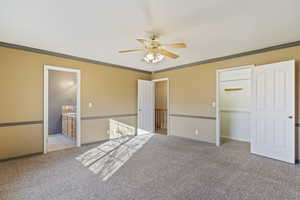 Unfurnished bedroom featuring ensuite bathroom, light carpet, ornamental molding, a closet, and ceiling fan