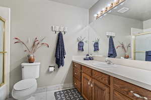 Full bathroom with shower / bath combination with glass door, vanity, toilet, and tile patterned flooring