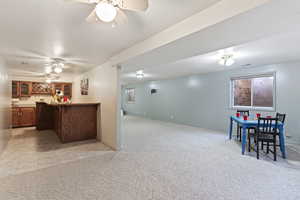 Kitchen featuring light carpet, kitchen peninsula, and ceiling fan