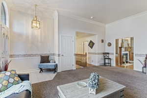 Living room featuring crown molding, light carpet, and a notable chandelier