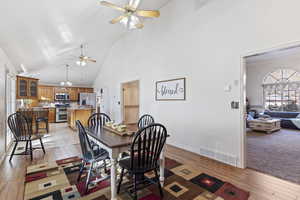 Dining space featuring ceiling fan, light wood-type flooring, and high vaulted ceiling