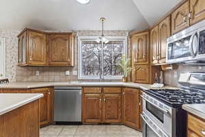 Kitchen featuring decorative light fixtures, lofted ceiling, sink, decorative backsplash, and stainless steel appliances