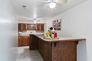 Kitchen with a kitchen breakfast bar, a textured ceiling, ceiling fan, and kitchen peninsula