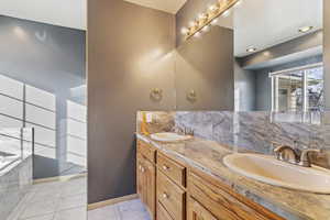 Bathroom with decorative backsplash, a tub to relax in, tile patterned floors, and vanity