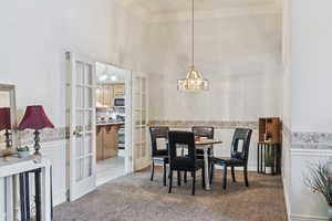 Dining space with french doors, carpet, and a notable chandelier