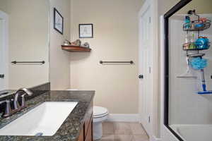 Bathroom with toilet, vanity, and tile patterned flooring