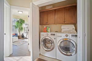 Washroom featuring light wood-type flooring, cabinets, and separate washer and dryer