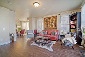 Living room with a wealth of natural light, dark hardwood / wood-style floors, and an inviting chandelier