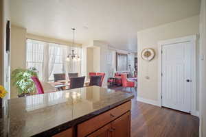 Kitchen featuring a textured ceiling, dark stone countertops, an inviting chandelier, pendant lighting, and dark hardwood / wood-style flooring