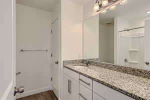 Bathroom featuring walk in shower, vanity, and hardwood / wood-style floors