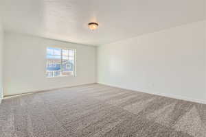 Carpeted spare room with a textured ceiling