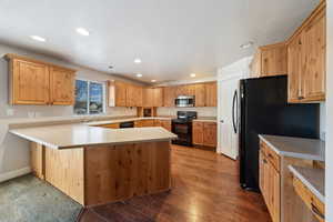 Kitchen featuring wood-type flooring, kitchen peninsula, sink, and black appliances