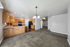 Kitchen featuring sink, dark carpet, black appliances, and kitchen peninsula