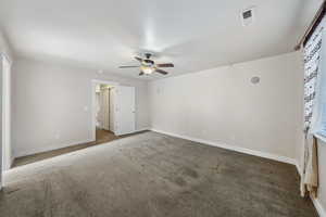 Unfurnished room with ceiling fan and dark colored carpet