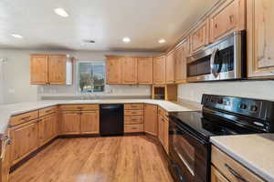 Kitchen with sink, light hardwood / wood-style flooring, and black appliances