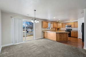 Kitchen with dark colored carpet, plenty of natural light, kitchen peninsula, and black appliances