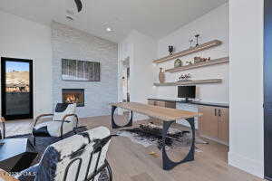 Office with lofted ceiling, a large fireplace, and light hardwood / wood-style floors