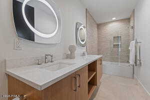 Bathroom featuring vanity and shower / bath combination with glass door