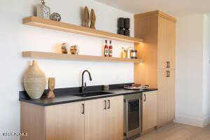 Bar with wine cooler, sink, and light brown cabinets