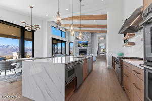 Kitchen with light stone counters, decorative light fixtures, a wealth of natural light, and a large island with sink