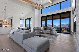 Living room with an inviting chandelier, a high ceiling, beam ceiling, a mountain view, and light wood-type flooring