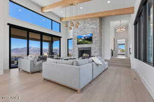 Living room with an inviting chandelier, a fireplace, light hardwood / wood-style floors, and beamed ceiling