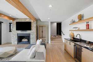 Living room featuring sink, light hardwood / wood-style flooring, and beamed ceiling