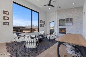 Living room with ceiling fan, a large fireplace, and hardwood / wood-style floors